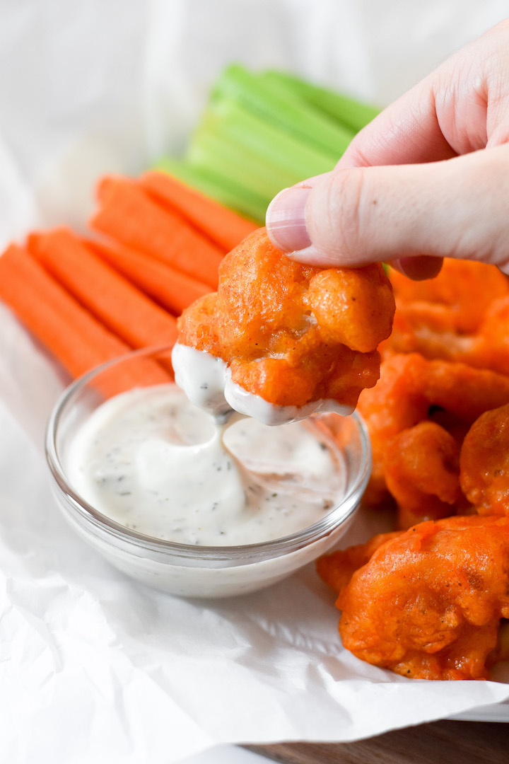 These vegan & gluten-free buffalo cauliflower wings are a game day hit! Crispy cauliflower florets tossed in a spicy buffalo sauce are a party appetizer that everyone can enjoy.