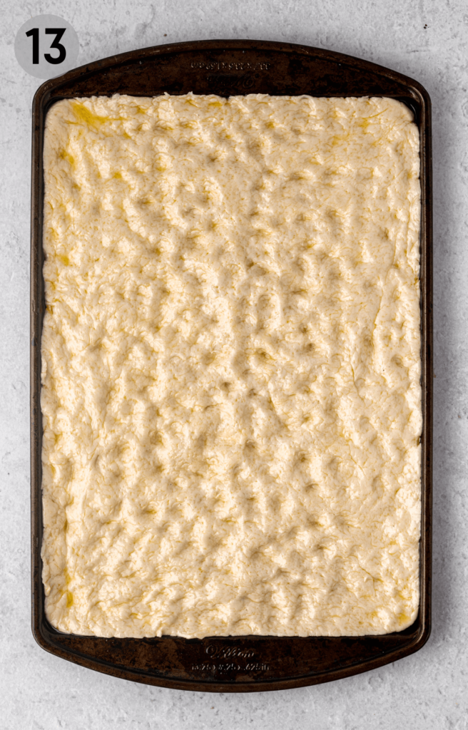 gluten free focaccia dough spread on a baking sheet
