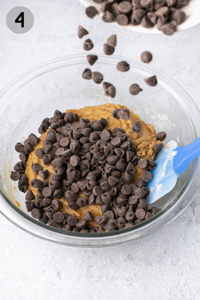 pouring chocolate chips into cookie dough