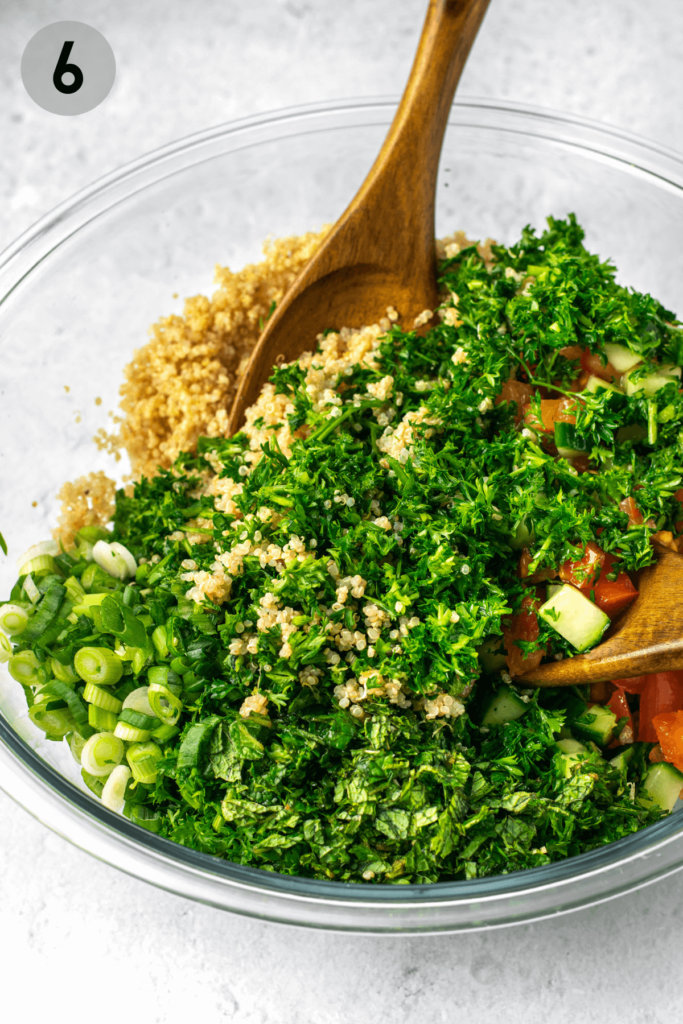 wooden spoons tossing together quinoa tabbouleh