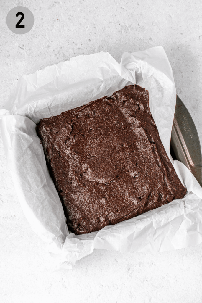 brownie batter in a parchment-lined baking dish