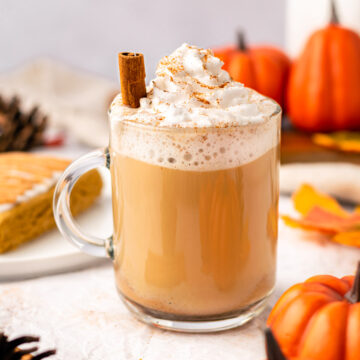 vegan pumpkin spice latte with a cinnamon stick and pumpkins around