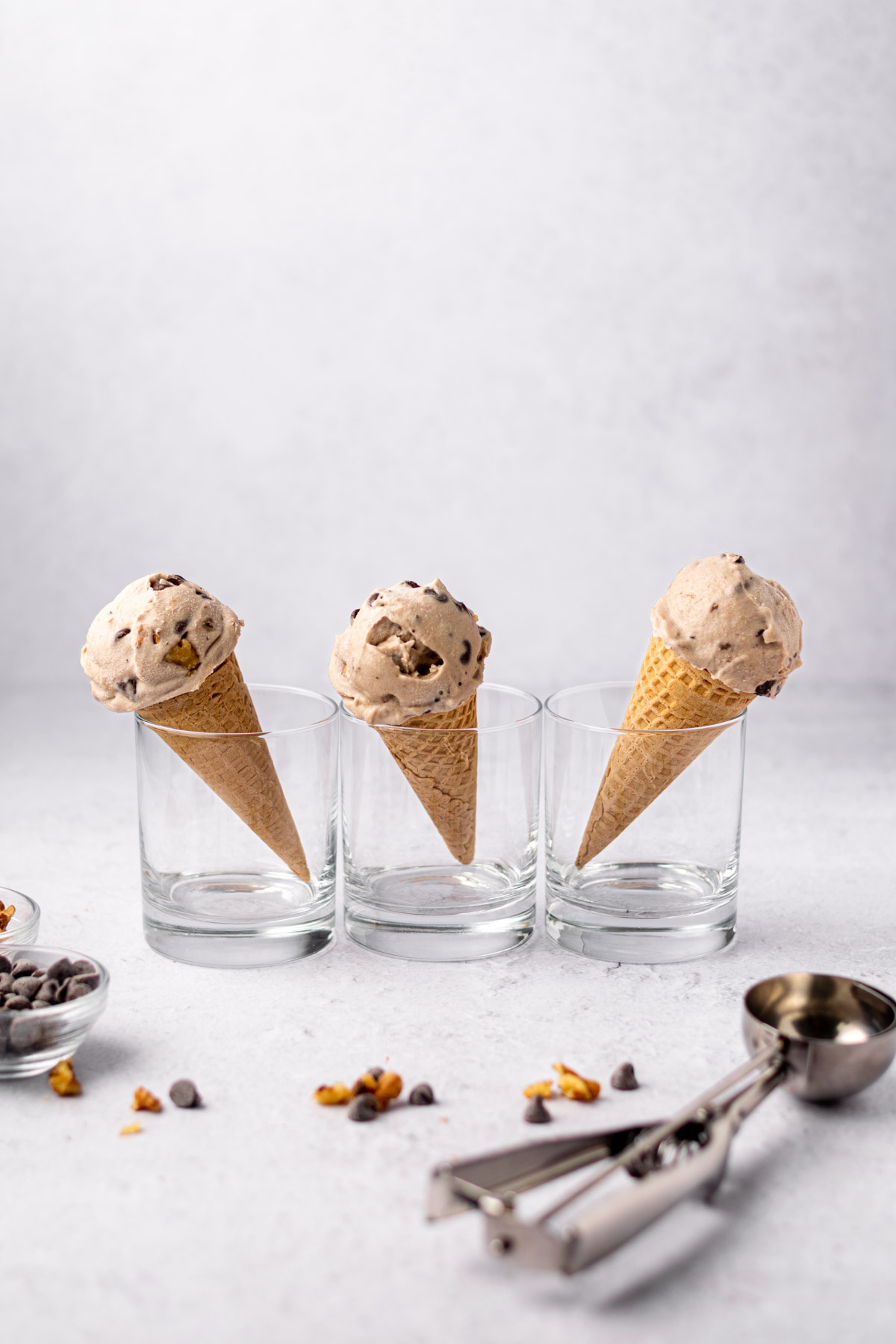 scoops of vegan chunky monkey ice cream on cones held up by cups