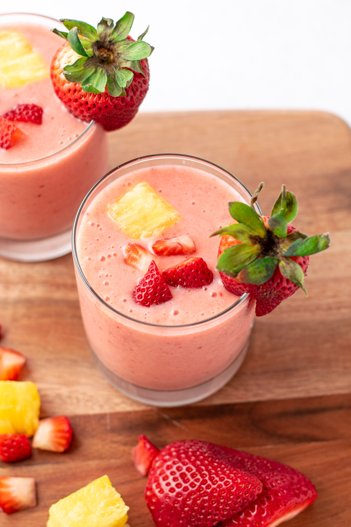 pink smoothie with strawberry and pineapple pieces on top