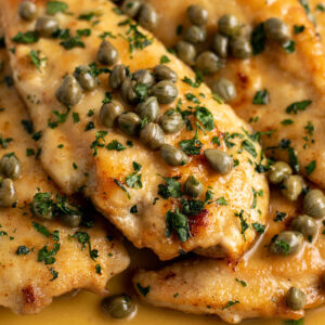 gluten free chicken piccata covered in capers and sauce on a plate.