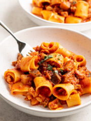 fork in a bowl of sausage and eggplant pasta.