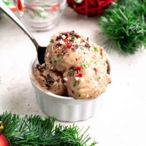 scoops of candy cane nice cream in a ramekin with a spoon.