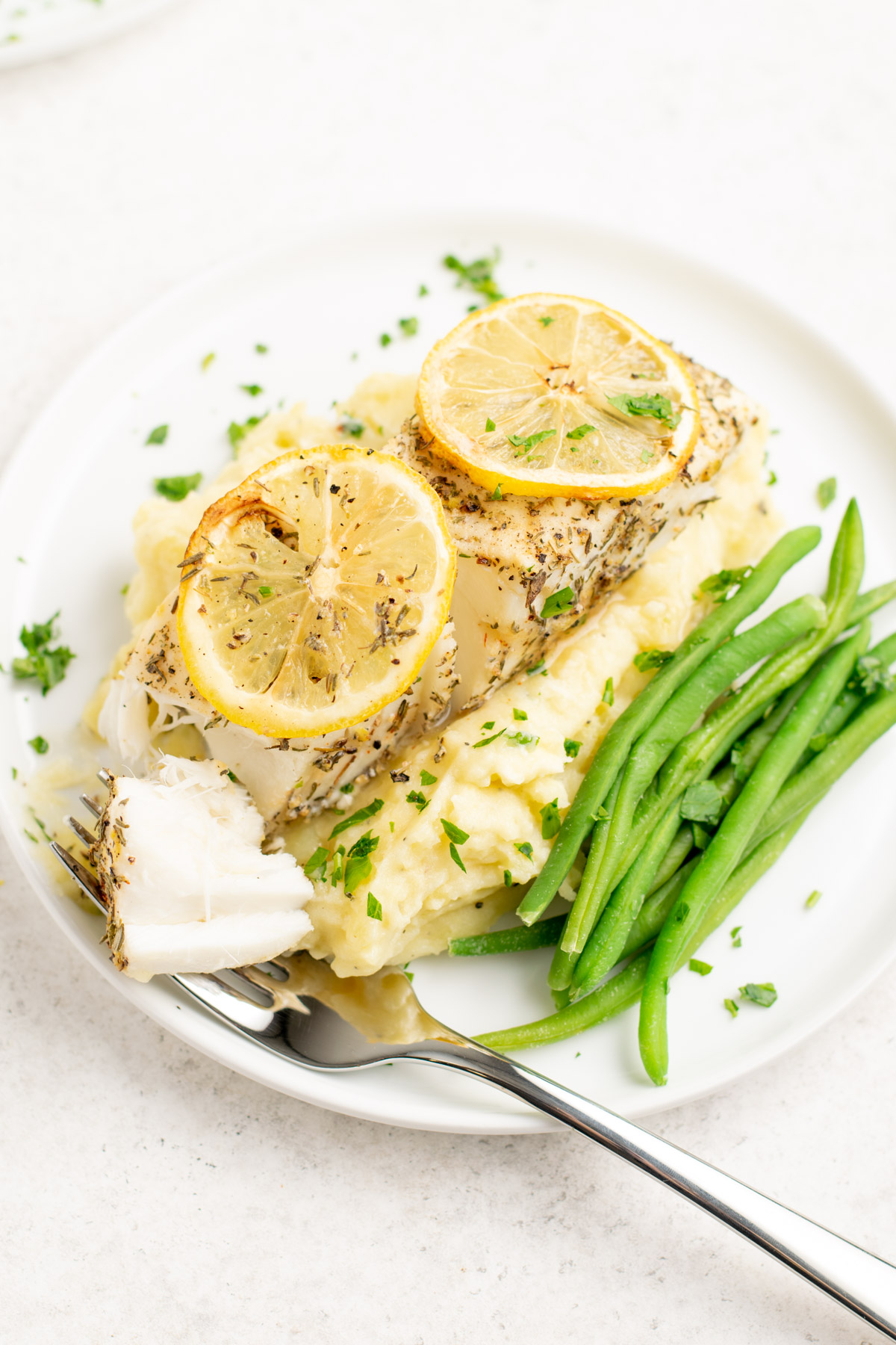 halibut topped with lemon slices and a fork with a pieces.