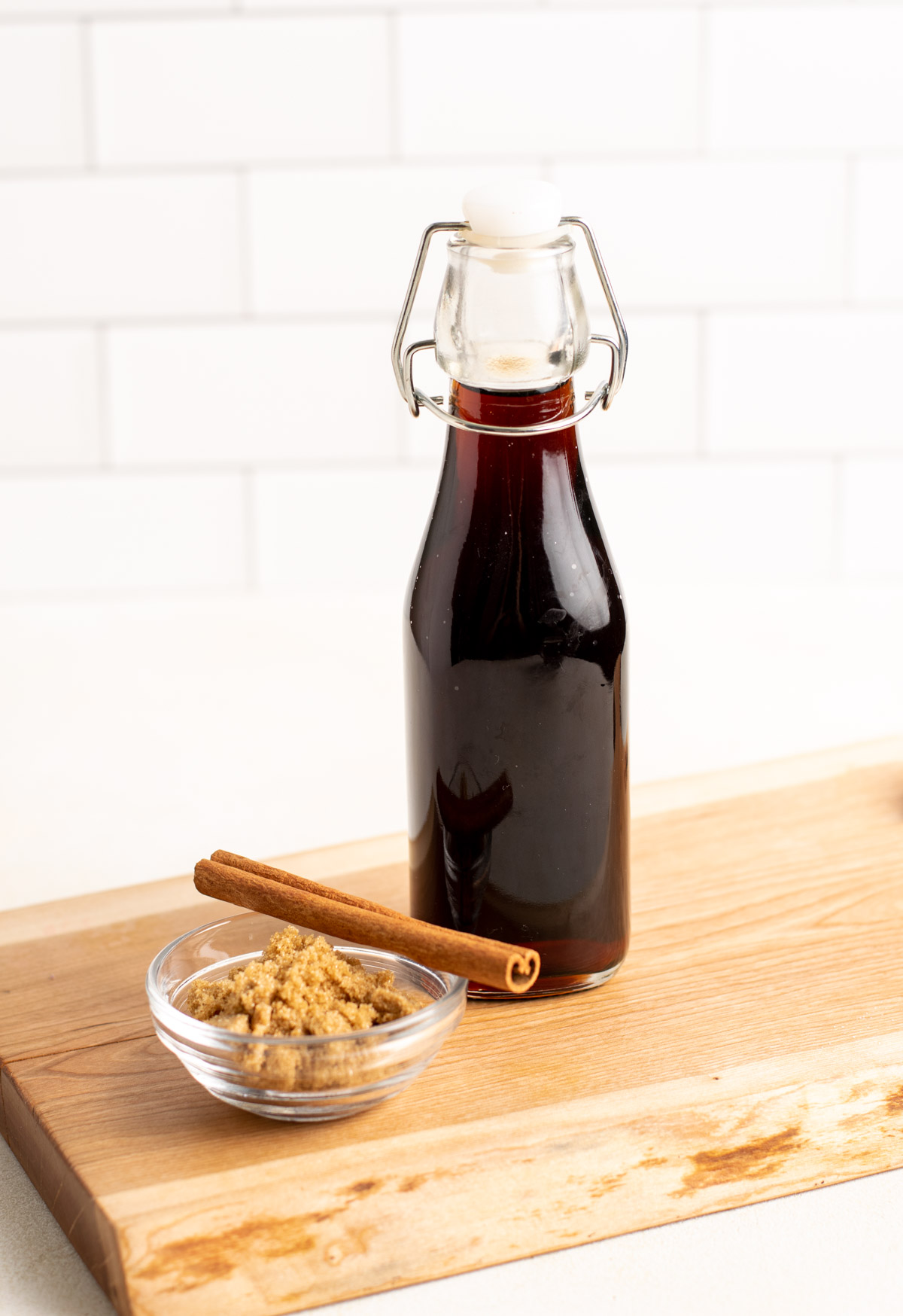 a glass jar of brown sugar syrup on a wood cutting board..
