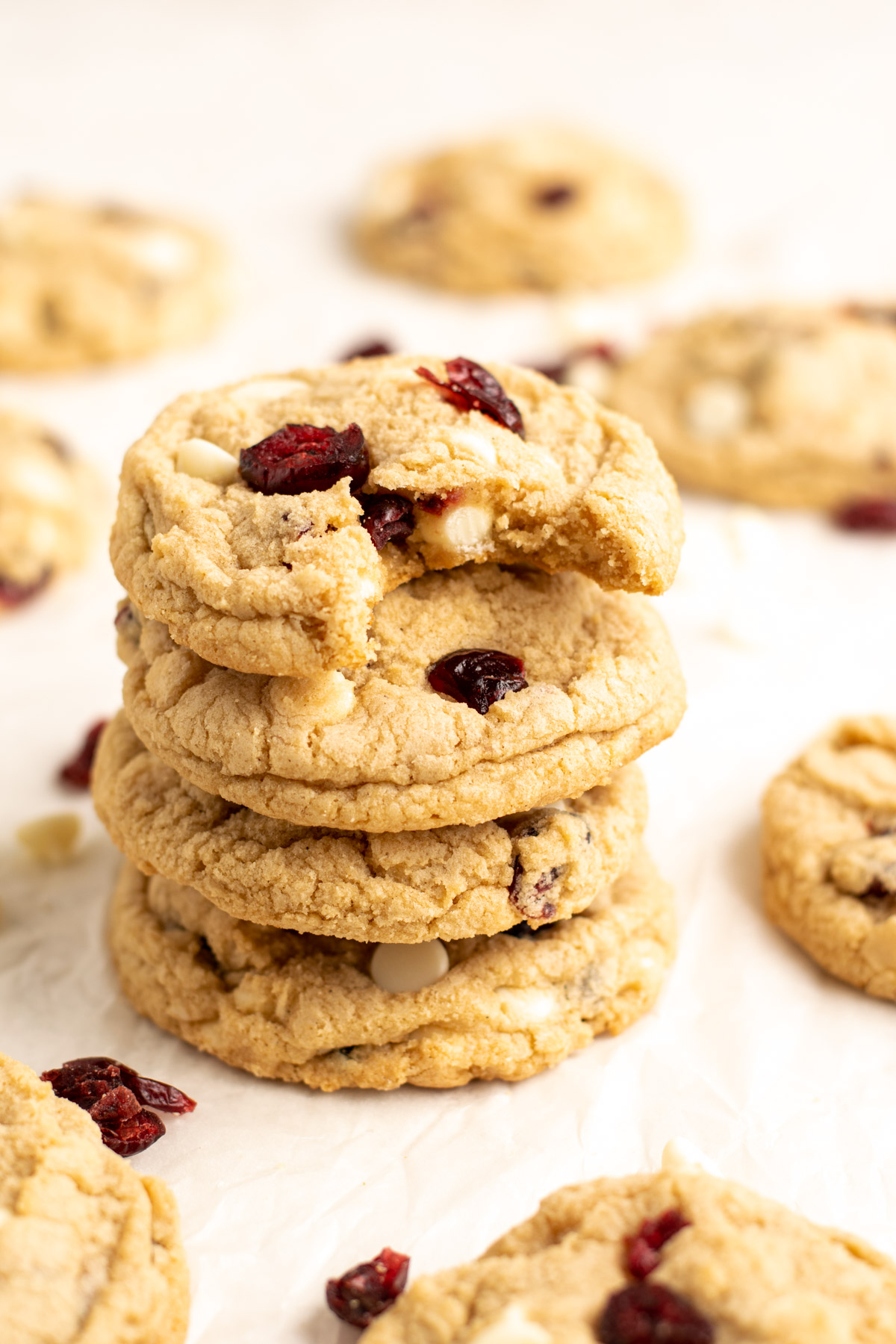 a stack of 4 gluten free white chocolate cranberry cookies, the top with a bite missing.