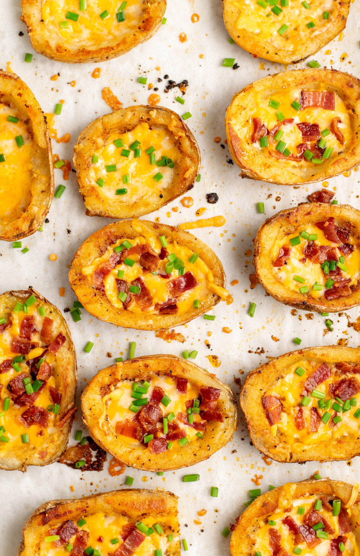 top view of loaded potato skins on parchment paper.