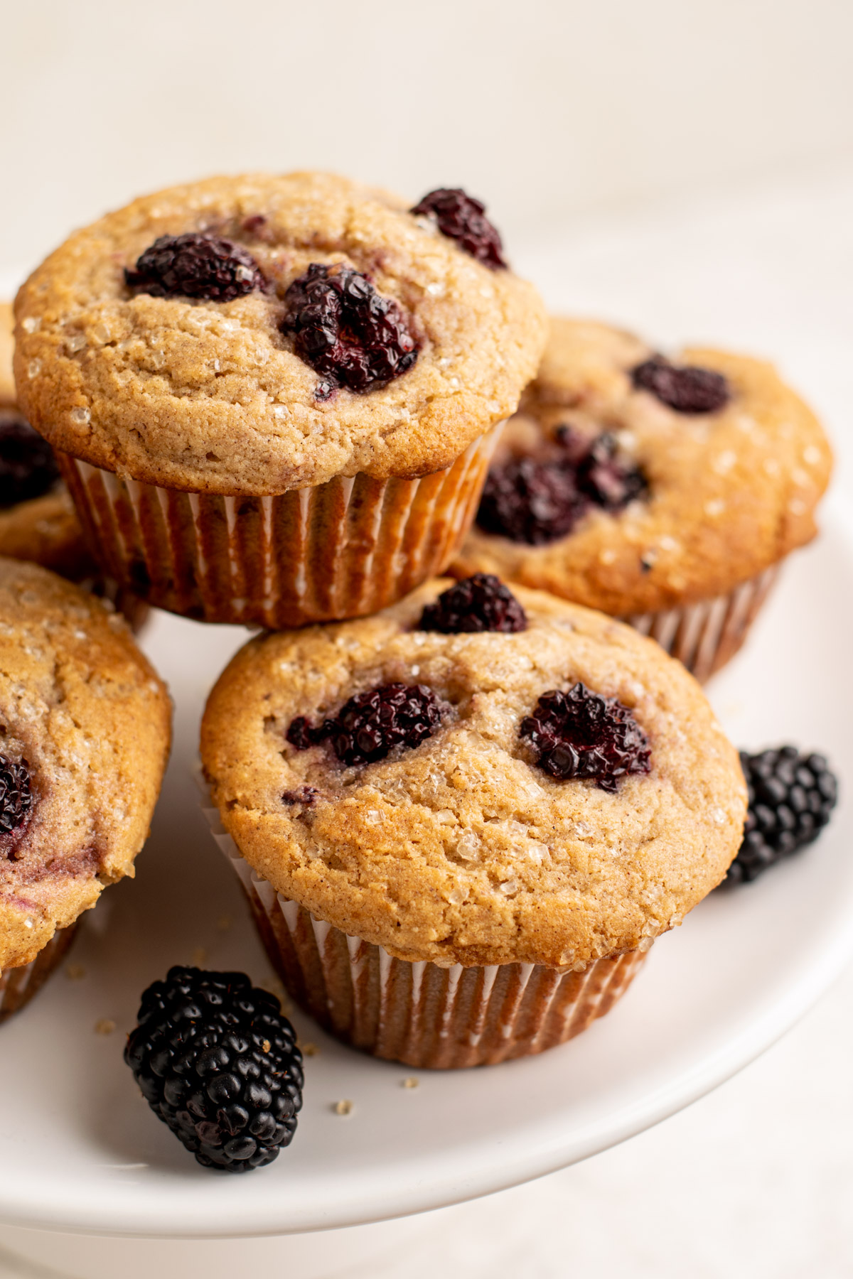 a stack of blackberry muffins on a white plate.