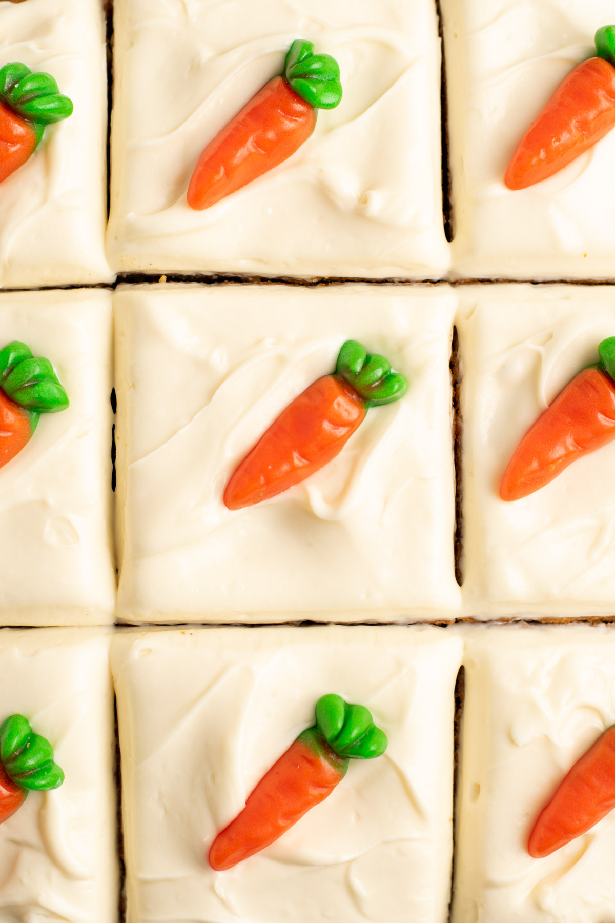 close up of candy carrots on top of squares of cream cheese icing.
