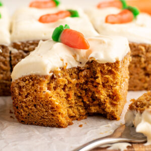 square of iced carrot cake with a bite missing.