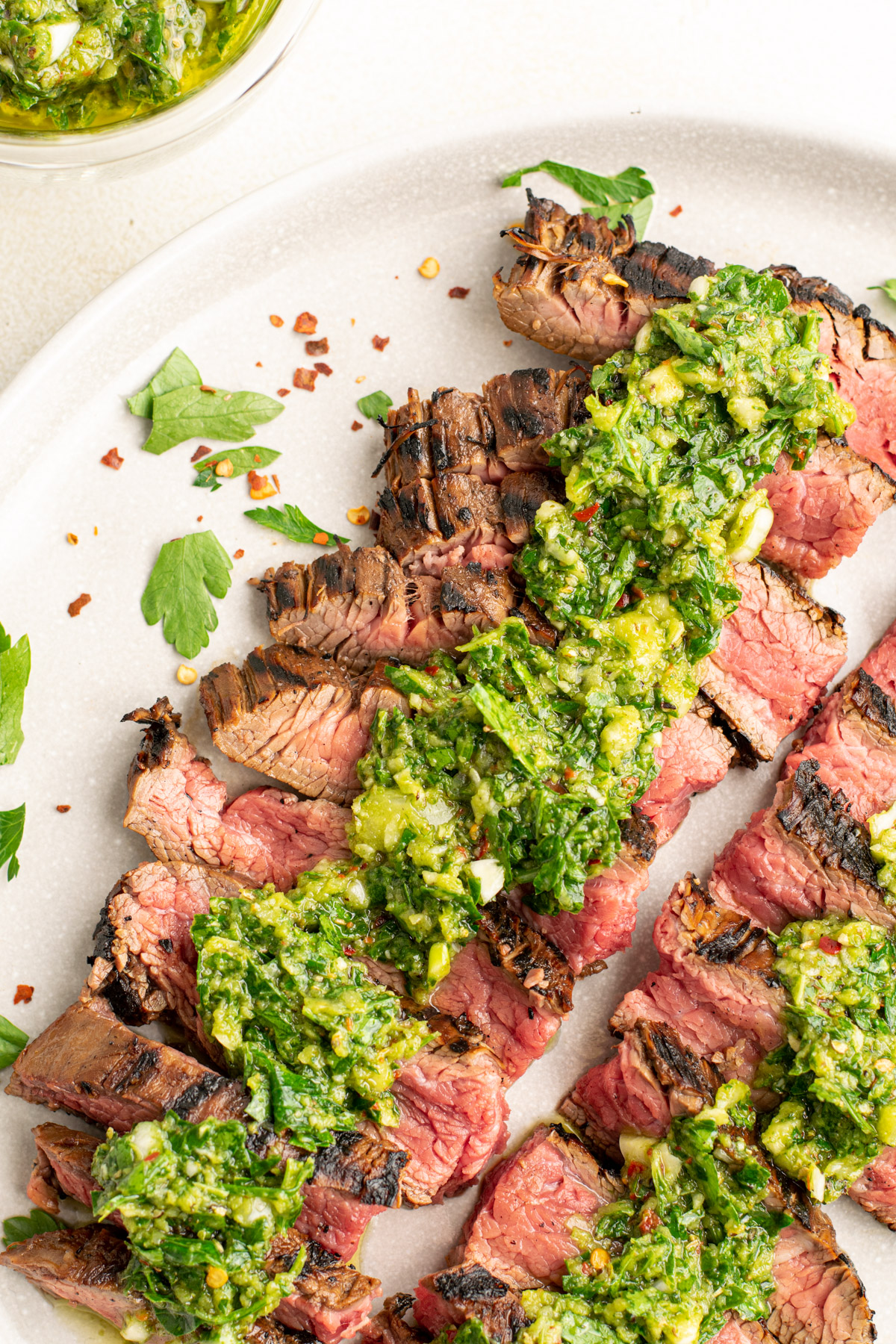 top view of sliced steak on a plate with chimichurri on top.