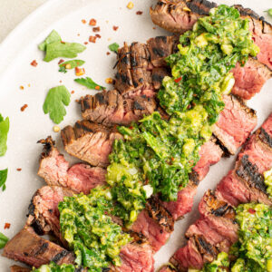 slices of flank steak with chimichurri on top.