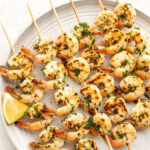 chimichurri shrimp skewers on a white plate.
