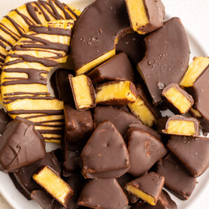 chocolate covered pineapple pieces on a white plate.