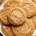 chocolate chipless cookies piled on a white plate topped with flaky sea salt.