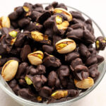 a glass bowl of chocolate covered pistachios.