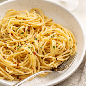 spaghetti aglio e olio in a white bowl with a fork.