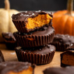 stack of 3 pumpkin peanut butter cups with the top one with a bite removed.