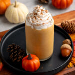 pumpkin spice protein shape with whipped cream on top and pumpkins around.
