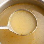ladle of rotisserie chicken bone broth over a pot.
