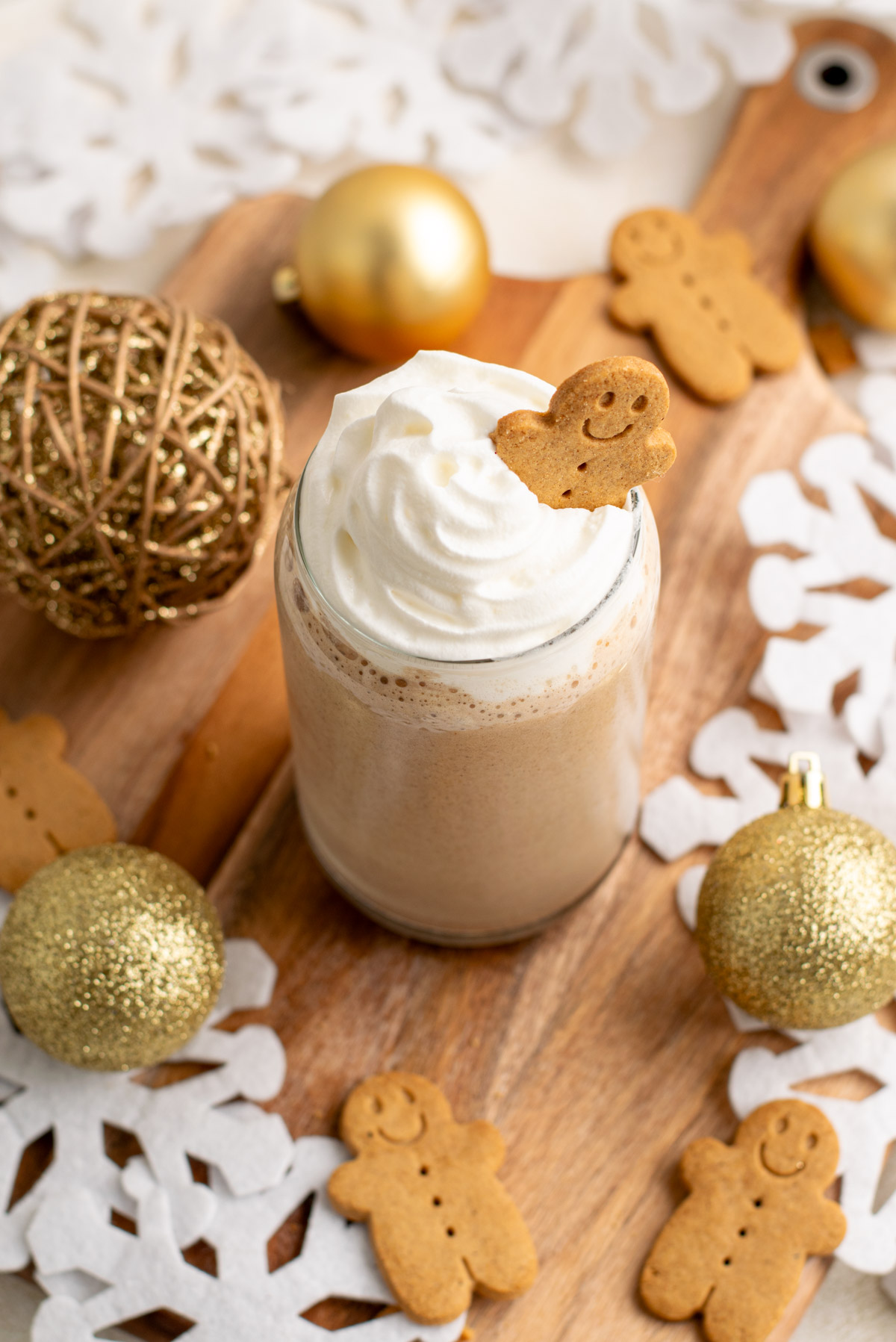 top view of a smoothie in a glass topped with whipped cream and a gingerbread man.