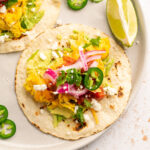 breakfast taco topped with red onion, jalapeno slices, cilantro, and cheese.