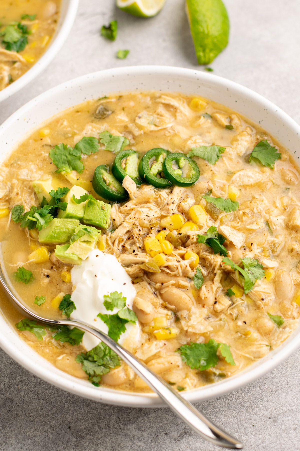 white chicken chili in a bowl topped with sour cream, avocado, jalapeño slices, and cilantro.