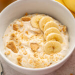 banana pudding greek yogurt bowl topped with sliced banana and crushed graham crackers.
