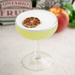 peach basil sour cocktail topped with a dehydrated lime.