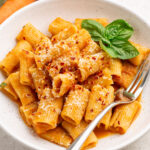 close up of roasted vegetable pasta topped with parmesan and pepper flakes.