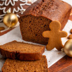 loaf of gingerbread banana bread with a gingerbread man cookie on the side.