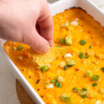hand scooping a chip into protein buffalo chicken dip.