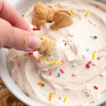 hand dipping an animal cracker into dunkaroo dip.