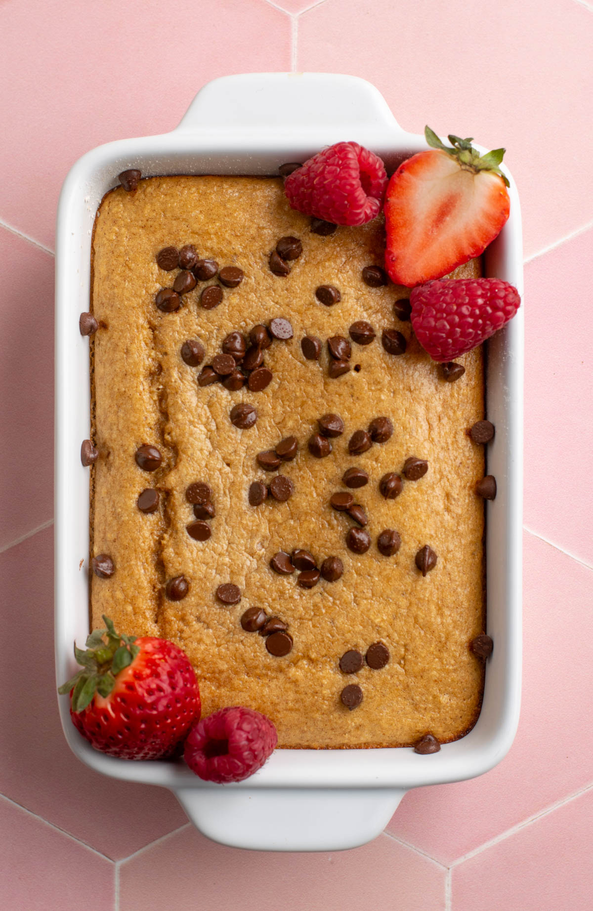 chocolate chip baked oats in a white dish with berries.
